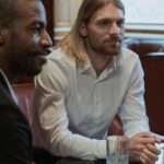 Two men in a formal setting engage in a business conversation at a restaurant.